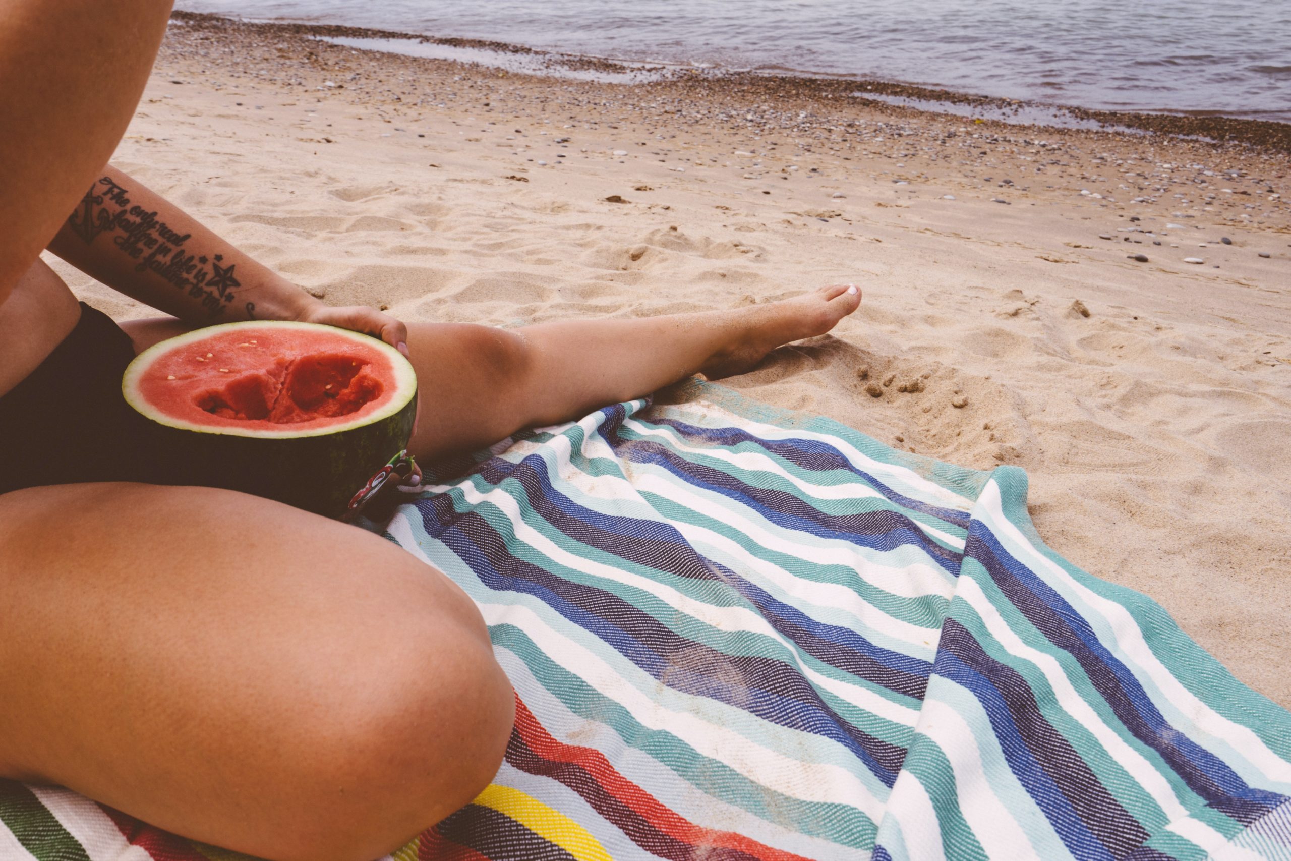 Anti-Inflammatory Diet woman eating watermelon on the beach scaled